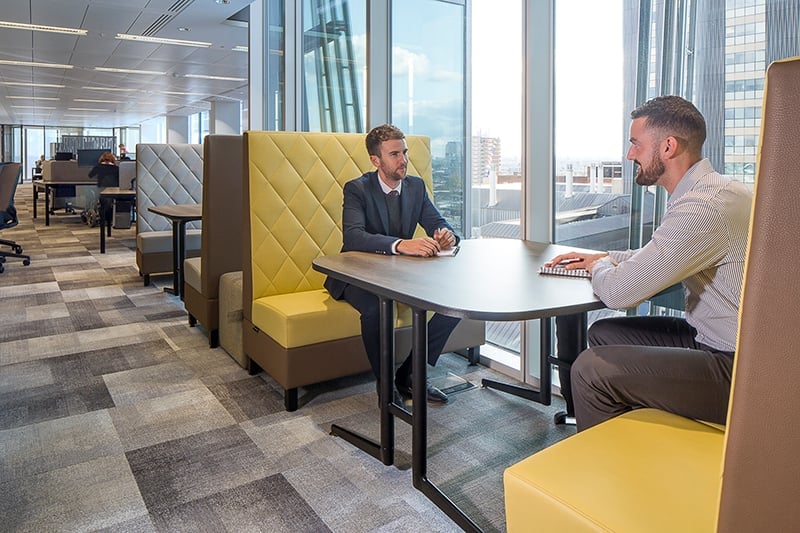 two men talking at a table in an office